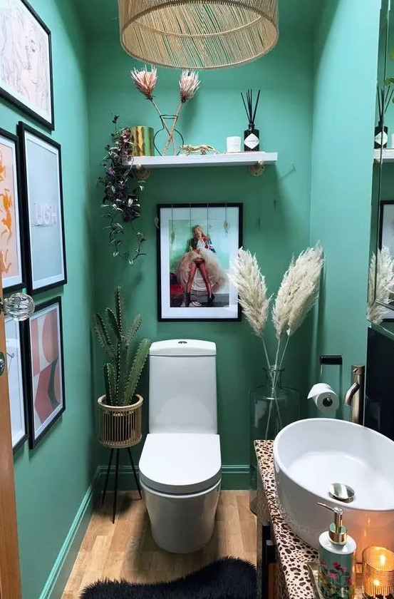 a small yet lovely emerald mudroom with a gallery wall, white appliances, pampas grass and a cactus, some candles