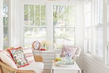 a small yet vibrant sunroom with neutral furniture, colorful printed textiles, a wicker pendant lamp and potted flowers