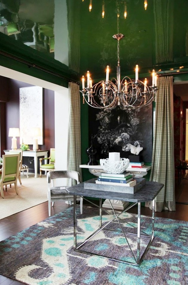 a sophisticated entryway with a glossy grene ceiling, a dark artwork, a console and a coffee table, a chic chandelier and a bold printed rug