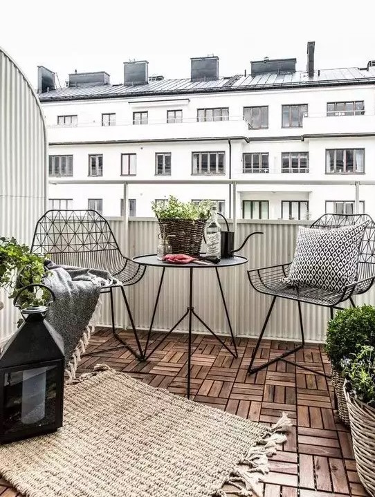 a stylish Scandinavian balcony with black metal chairs and a coffee table, candle lanterns and potted plants is a very stylish idea for a Nrodic style lover