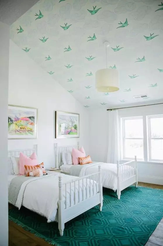 a stylish double guest bedroom with an attic ceiling covered with green bird wallpaper and a matching rug