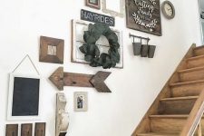 a stylish gallery wall with wooden arrows and signs and artworks in stained frames, mirrors and vintage window frames