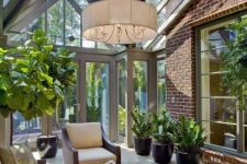 a stylish mid-century modern sunroom with elegant dark furniture, potted greenery, a pdant lamp and much light