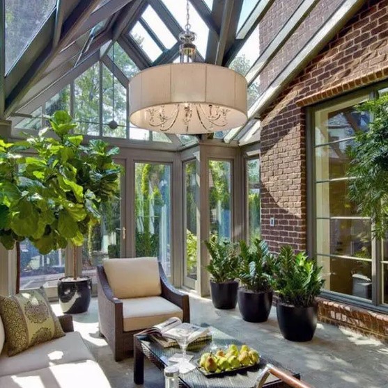a stylish mid-century modern sunroom with elegant dark furniture, potted greenery, a pdant lamp and much light