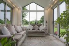 a stylish modern sunroom with elegant sofas, potted greenery and nice views is welcoming