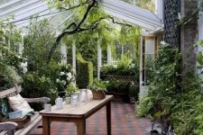 a sunroom styled as an orangery with lots of greenery and blooms, wooden furniture and candle lanterns