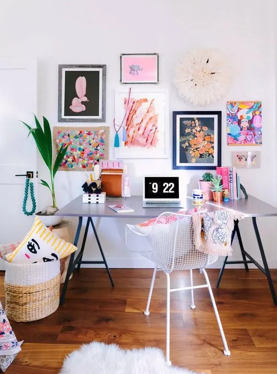 a super bright and girlish home office with a lightweight desk, a white chair, a colorful gallery wall and a basket with pillows