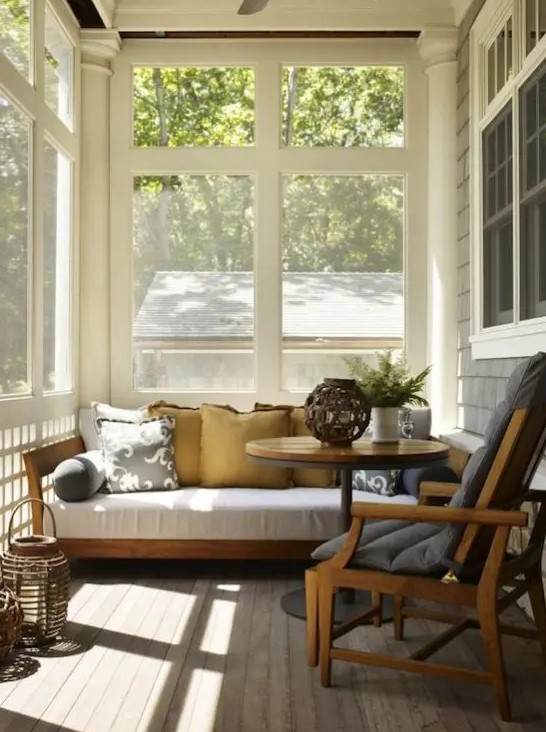 a tiny mid-century modern sunroom with some comfortable furniture, wicker lamps and potted greenery