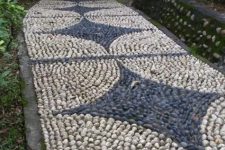 a very bold and eye-catchy neutral and grey pebble pathway with creative patterns and brick lining up