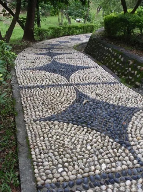 a very bold and eye catchy neutral and grey pebble pathway with creative patterns and brick lining up