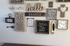 a vintage farmhouse gallery wall with simple wooden signs, an ampersand, keys, a clocj and other stuff