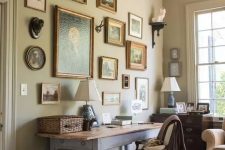 a vintage home office with a whitewashed desk, a white chair, baskets, a chic vintage gallery wall, a stained dresser and a wooden chandelier