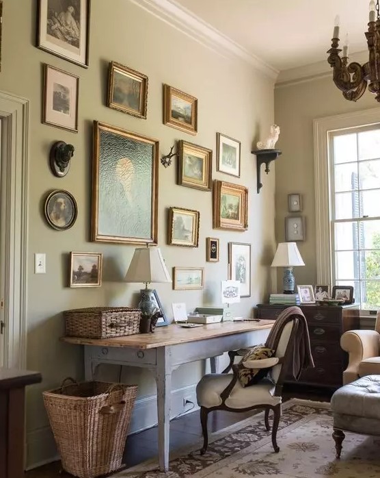 a vintage home office with a whitewashed desk, a white chair, baskets, a chic vintage gallery wall, a stained dresser and a wooden chandelier