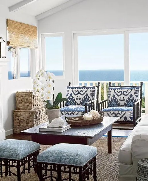 a vintage rustic coastal sunroom with dark wooden furniture with blue upholstery, baskets, shades and a white sofa plus a cool view