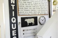 a vintage rustic gallery wall with signs in frames, railing pieces, greenery, rope and some signs on the shelf
