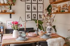 a welcoming dining space with a stained table and black chairs, stained shelves and a grid black and white gallery wall and potted greenery