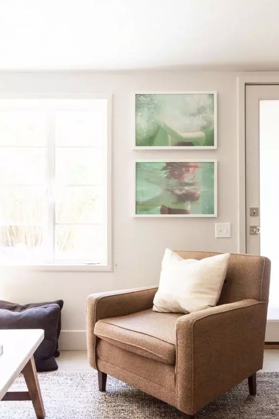 a welcoming neutral living room with light grey walls, a brown chair, a mini gallery wall with personal photos