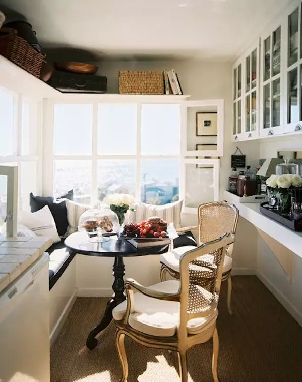 a welcoming small sunroom turned into a dining space, with storage cabinets, an L-shaped bench with storage and chairs
