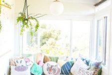 a welcoming sunroom with a sofa and lots of pillows, with footrests and potted greenery