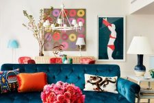 a whimsical living room with a glossy mint blue ceiling, a navy tufted sofa, a colorful printed rug and bold artwork on the wall