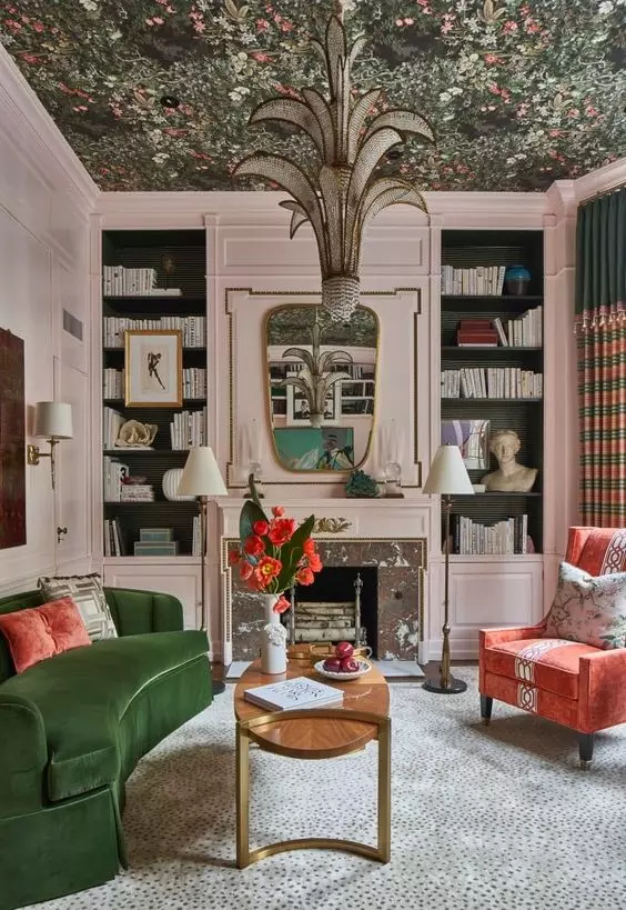 a whimsical living room with blush walls and paneling, a floral wallpaper ceiling, a gren sofa and a coral chair, a unique chandelier