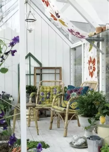 a white boho sunroom with colorful painted flowers, bright upholstery and pillows, potted plants and blooms in bold colors