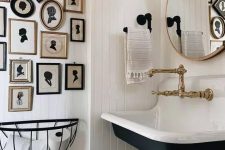 a white farmhouse bathroom with planked walls, a navy wall-mounted sink, a vintage silhouette gallery wall and vintage fixtures