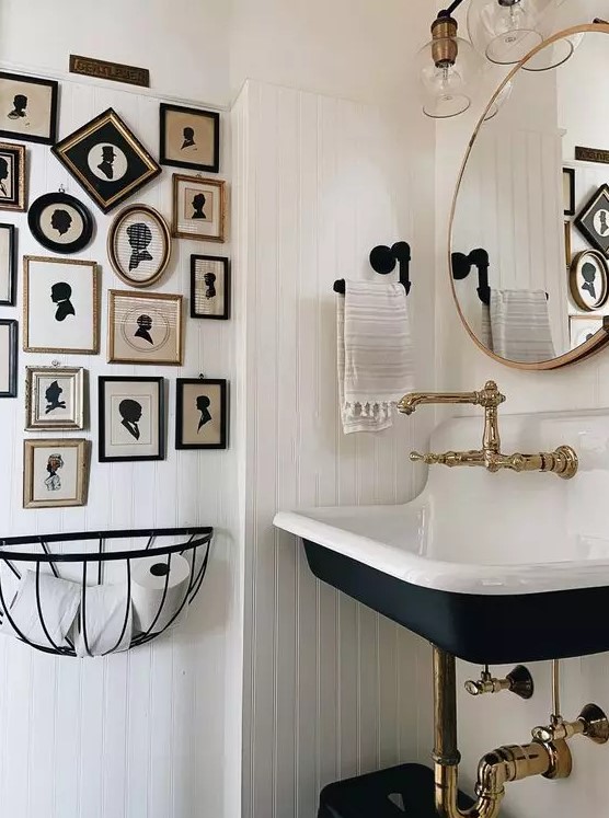 a white farmhouse bathroom with planked walls, a navy wall mounted sink, a vintage silhouette gallery wall and vintage fixtures