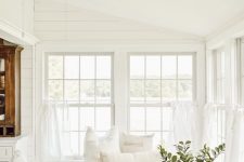a white farmhouse sunroom with a built-in daybed with storage drawers, a sofa, a dresser and a potted plant is amazing