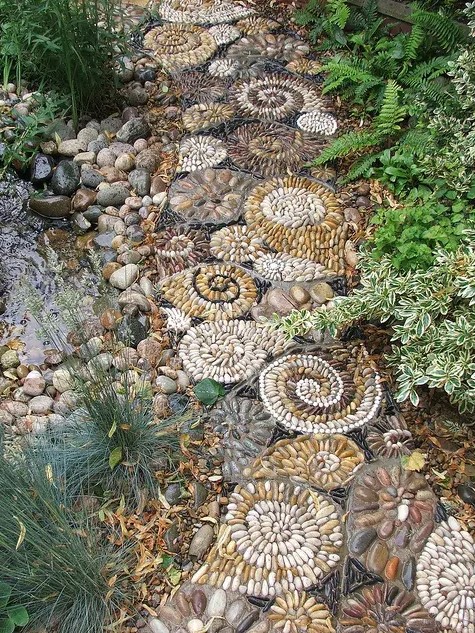 an earthy tone pebble path that imitates amonites is a great idea to go for next to a water feature like a pond here