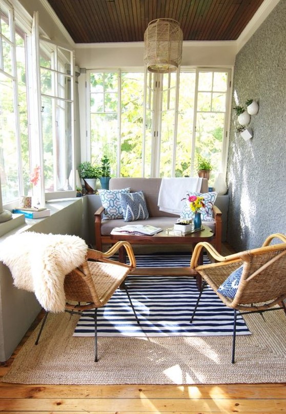 an eclectic and boho sunroom with wicker chairs and lamps, with layered rugs and touches of color