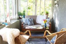 an eclectic and boho sunroom with wicker chairs and lamps, with layered rugs and touches of color
