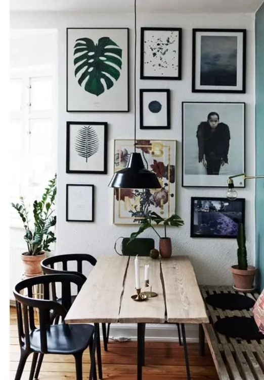 an eclectic dining room with a planked table, a pallet bench and black chairs plus a lovely free form gallery wall