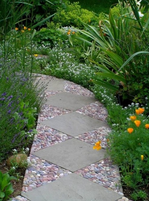 an eye catchy garden path done with large grey tiles and red, blue and white pebbles around them