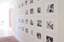 an oversized black and white family gallery wall featuring white matting and frames looks very lightweight and airy