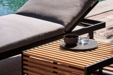 catchy modern outdoor furniture – a black metal lounger with grey upholstery and a metal and wood side table are a great combo