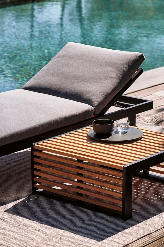 catchy modern outdoor furniture - a black metal lounger with grey upholstery and a metal and wood side table are a great combo