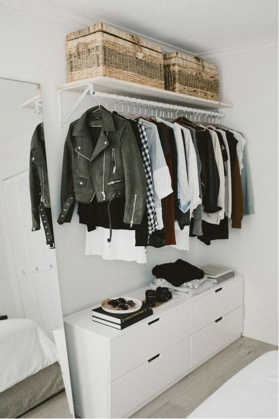 a small yet chic makeshift closet with a holder with hangers, a dresser, woven baskets can be placed in a bedroom