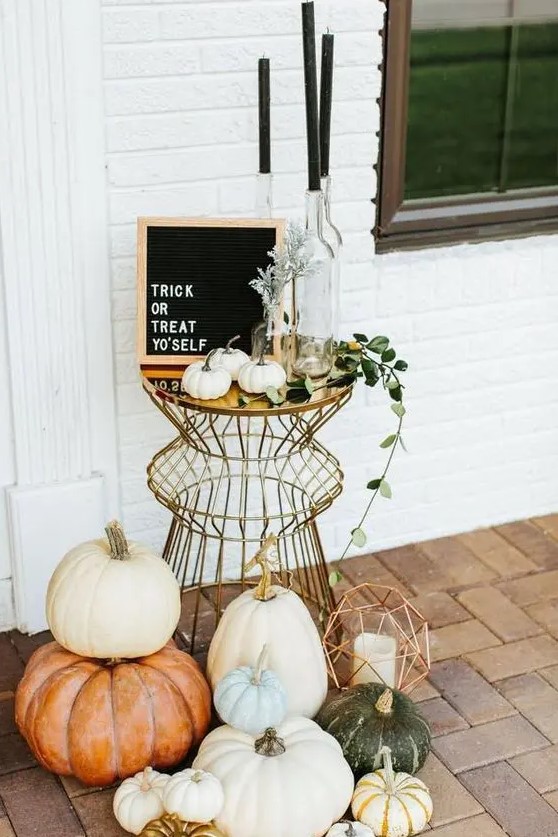a stylish modern display with lots of pumpkins, geometric lanterns, black candles and a black framed sign