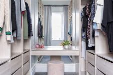 10 a neutral minimalist closet of neutral plywood, with a large mirror in the center and a velvet ottoman
