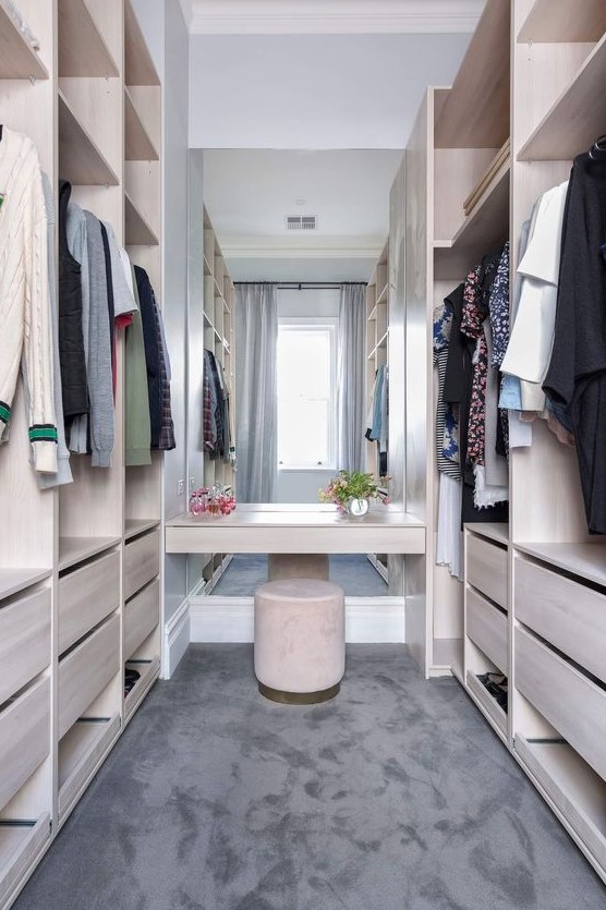a neutral minimalist closet of neutral plywood, with a large mirror in the center and a velvet ottoman