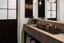 10 an industrial chic bathroom with a glazed shower space, a concrete vanity with a double sink, a rough wooden floor, exposed pipes and bulbs