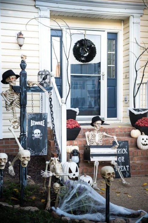 a skeleton porch with several skeletons, skulls, skeleton hands, a black wreath, a sign and spiderwebs looks impressive