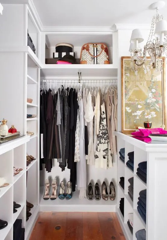 a small and glam closet in white, with built in shelves and wardrobes, with an open storage cabinet and a glam crystal chandelier