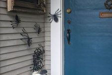 13 paper spiders on the walls, black and white pumpkins, a spiderweb wreath and a sign for simple and fast Halloween decor