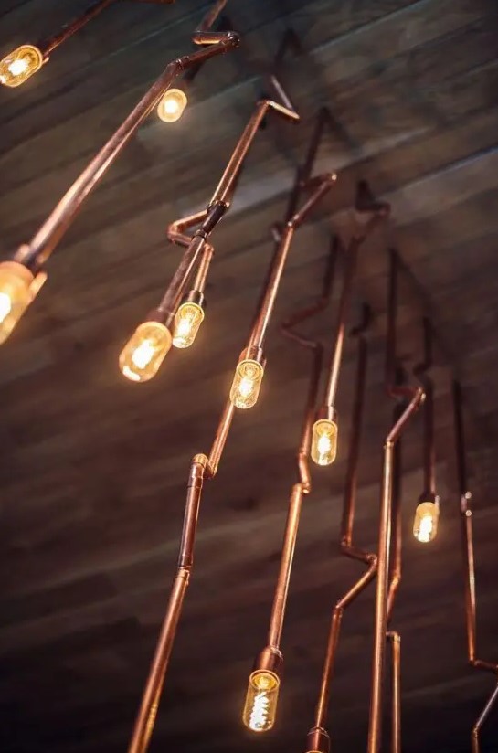 a cluster of copper pipes with bulbs looks spectacular and super cool and will make your space look bolder and lovelier
