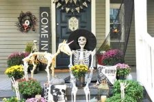 25 a creative Hallowene porch with a skeleton and a skeleton dog, candle lanterns, blooms and greenery and signs and buntings