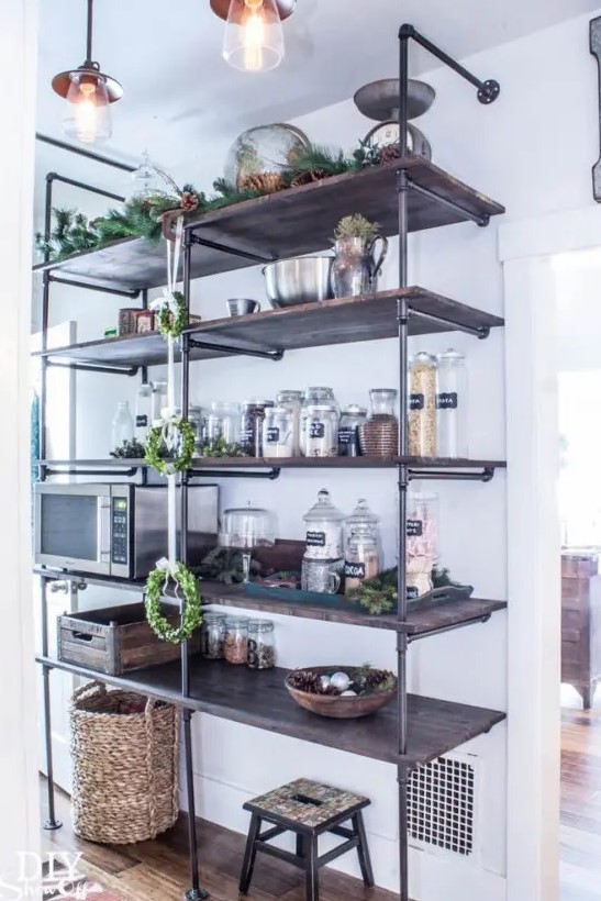 a large industrial shelving unit composed of exposed pipes and stained wood is a cool solution for an industrial or rustic pantry or kitchen