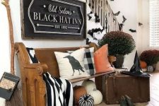 28 a farmhouse entryway with a wooden bench, pillows and a striped blanket, potted plants and a black vintage sign