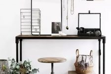 29 a small and pretty industrial working space with a metal console table, a metal pipe and wood stool, various jewelry on stands and some decor